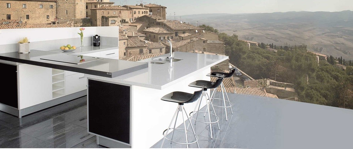 Modern kitchen with a sleek marble worktop overlooking a rustic Italian village